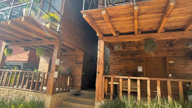 Una cabaña de madera con balcón, porche y una escalera que lleva a la entrada.