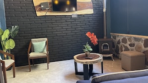 Un espacio de estar acogedor con pared de ladrillo, televisor de pantalla plana montado en un estante de madera, chimenea de piedra y asientos cómodos.