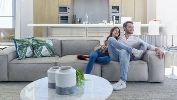 Una sala moderna con un sofá, una mesa de centro y una cocina al fondo.