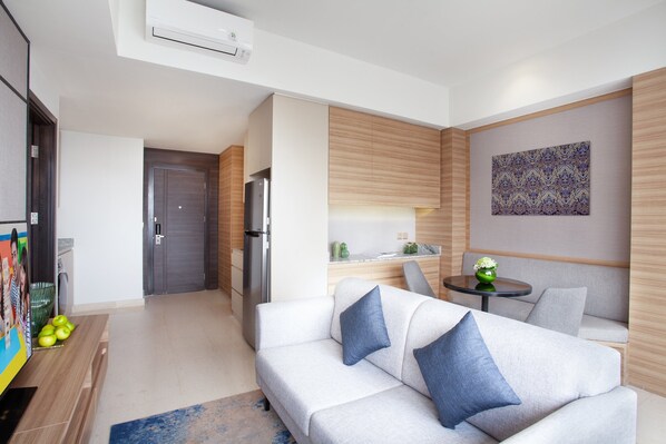 A modern living room with a sofa, a small table, and a kitchen area in the background. - Somerset Sudirman Jakarta (Jakarta)