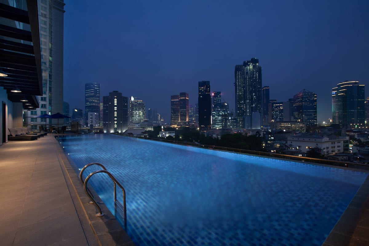 Piscina en la azotea con vista al horizonte urbano al atardecer.