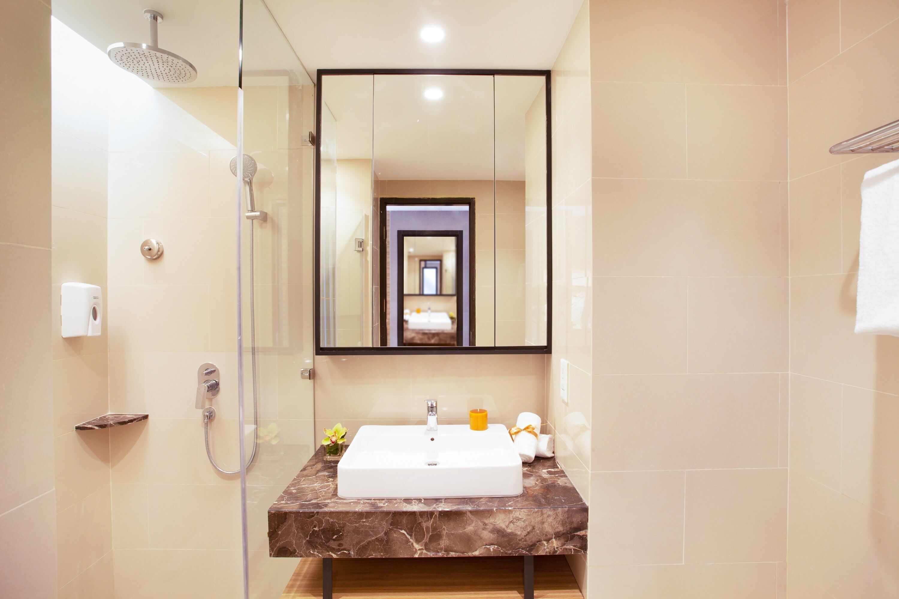 Une salle de bain moderne avec une douche à parois de verre, un lavabo en marbre et un grand miroir.