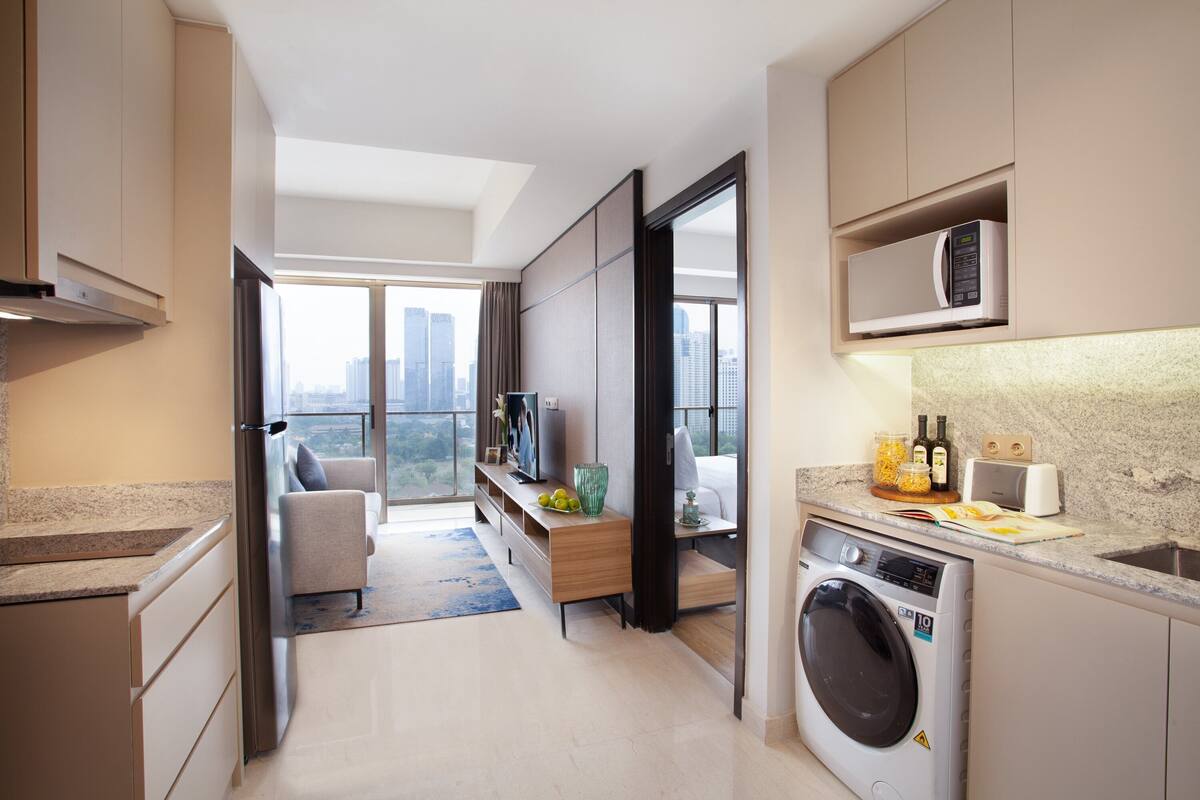 Una cocina moderna con lavadora incorporada, microondas y comedor con vistas a la ciudad.