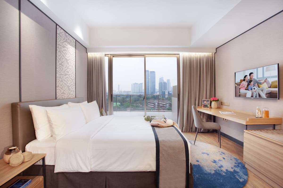 Una habitación de hotel moderna con una cama grande, un escritorio y vistas a la ciudad.