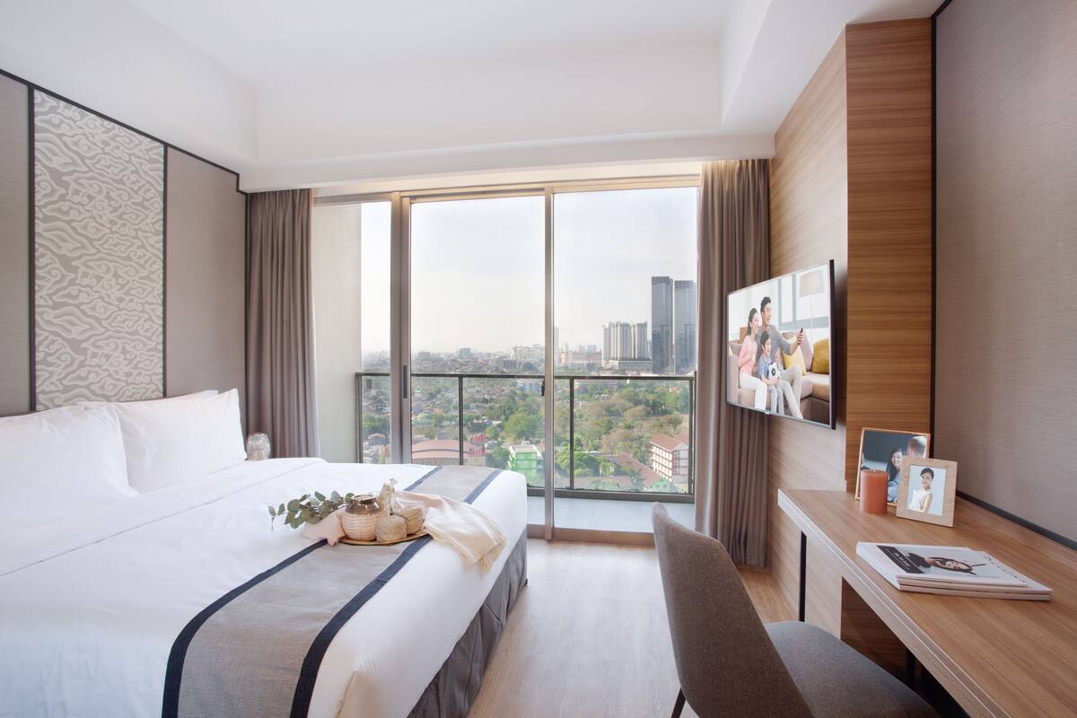 Una habitación de hotel con una cama grande, un escritorio y un televisor.