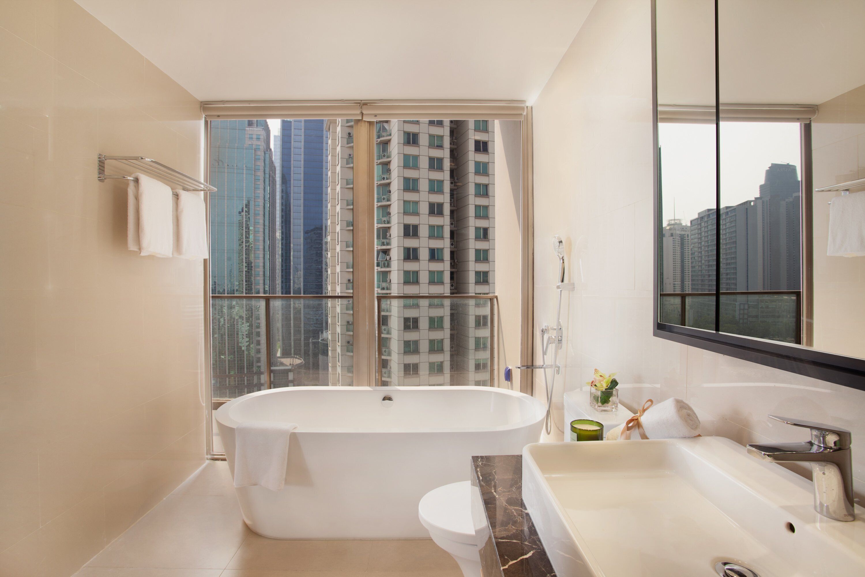 A modern bathroom with a bathtub, a vanity with a sink, and a large mirror.