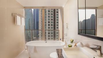 A modern bathroom with a bathtub, a vanity with a sink, and a large mirror.
