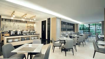 A modern dining area with tables and chairs, a marble backsplash, and a view through large windows.