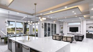 A modern kitchen with a large island, built-in appliances, and a dining area with outdoor seating. - The Modern Jewel | 10BR Luxury Estate w/ Themed Rooms, Private Pool, Arcade, and Theater Near Disney (Kissimmee)