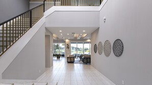 A spacious interior with a staircase, a seating area, and decorative wall art. - The Modern Jewel | 10BR Luxury Estate w/ Themed Rooms, Private Pool, Arcade, and Theater Near Disney (Kissimmee)
