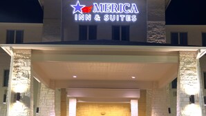 A building with a sign reading "America Inn & Suites" featuring a star and a red heart. - Merica Inn & Suites (Wills Point)