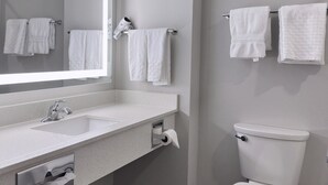 A modern bathroom with a large mirror, a sink, a toilet, and two towel racks. - Merica Inn & Suites (Wills Point)