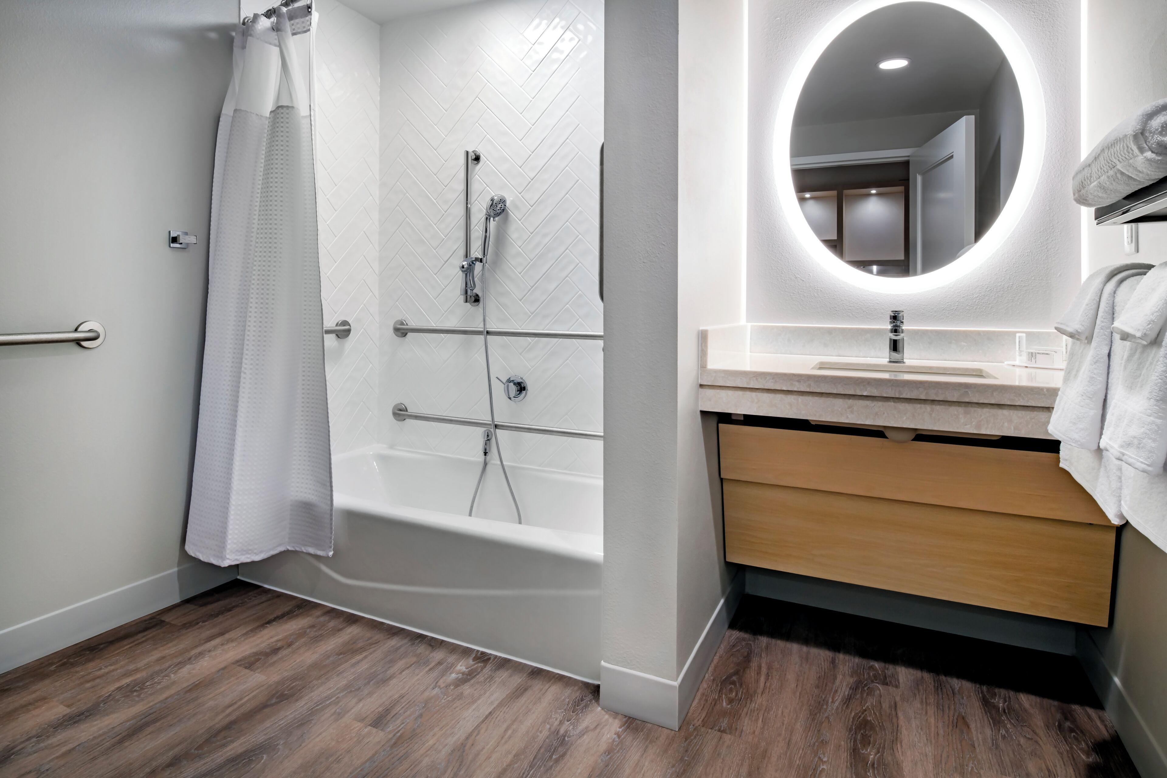 A modern bathroom with a shower, a sink with a mirror, and wooden cabinetry.