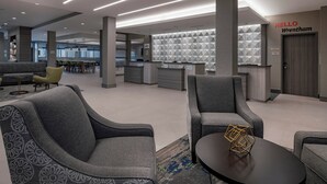 A modern lobby with grey sofas, a reception desk, and a geometric patterned wall. - TownePlace Suites by Marriott Wrentham Plainville (Plainville)