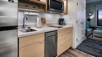 Una cocina compacta con un refrigerador de acero inoxidable, un microondas y un lavavajillas.