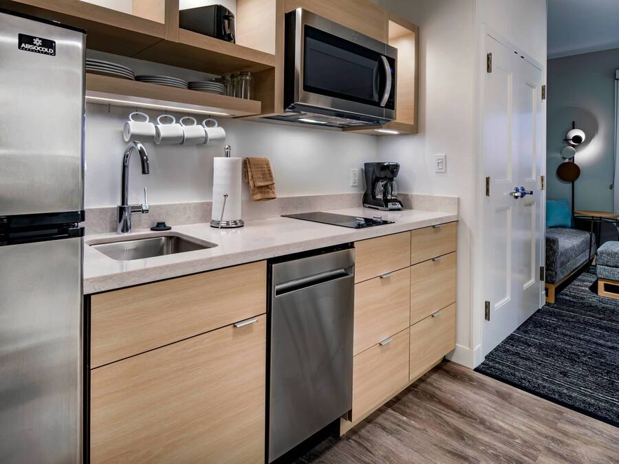 Una cocina compacta con un refrigerador de acero inoxidable, un microondas y un lavavajillas.