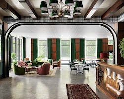 Un vestíbulo espacioso con techo curvo, ventanas amplias y una variedad de zonas de estar con sofás y sillones.