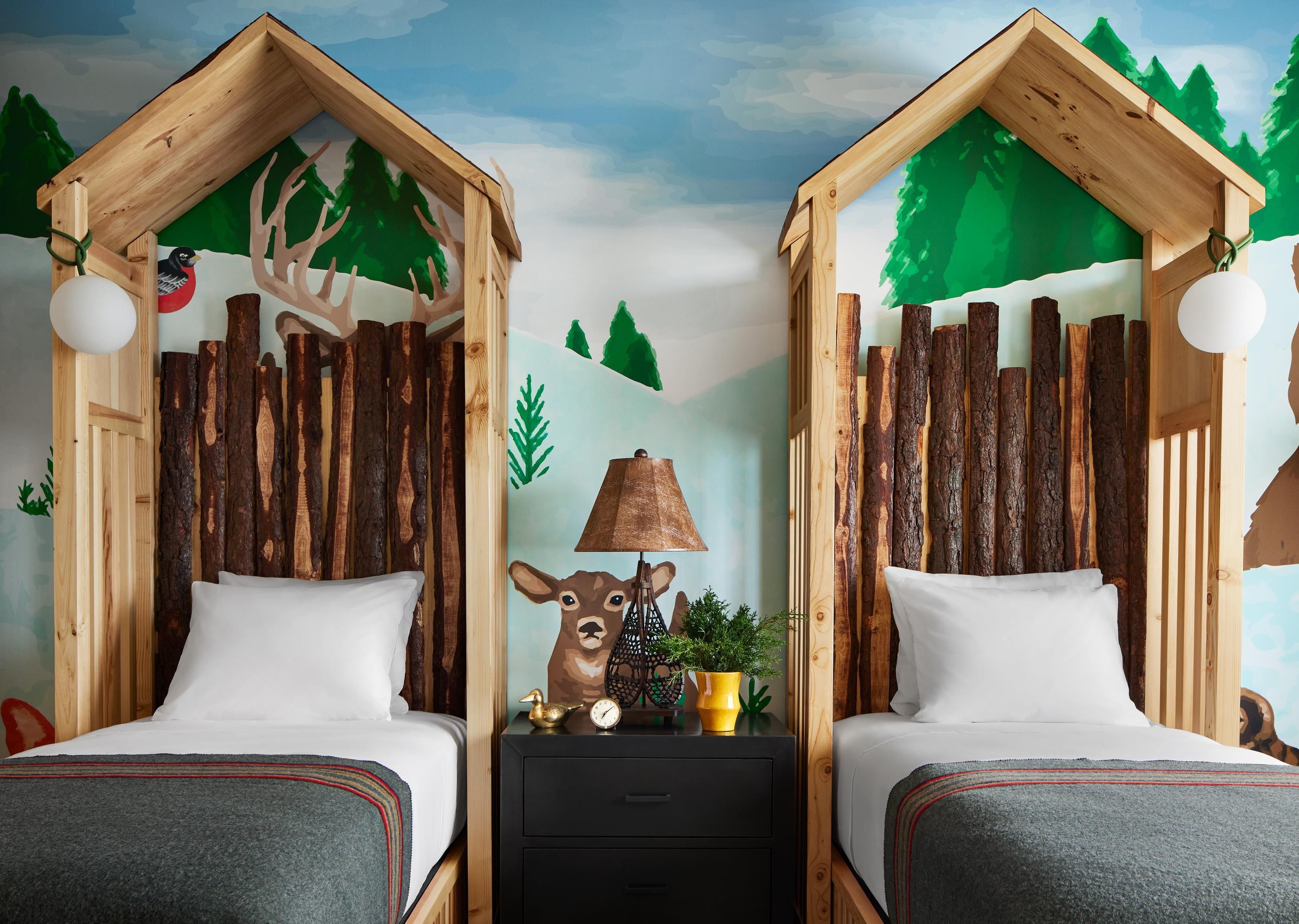 A room with two wooden beds, a nightstand with a lamp, a clock, and a small plant.