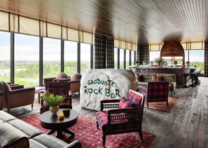 A spacious lounge area with a bar, comfortable seating, and a large window offering a view of the outdoors.