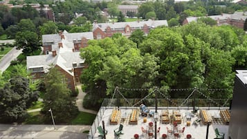 A rooftop terrace with outdoor seating and a view of a campus.