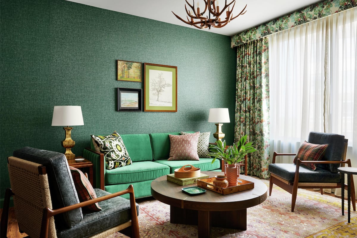 Un salon décoré dans les tons de vert, avec un canapé, des fauteuils, une table basse et des coussins décoratifs.