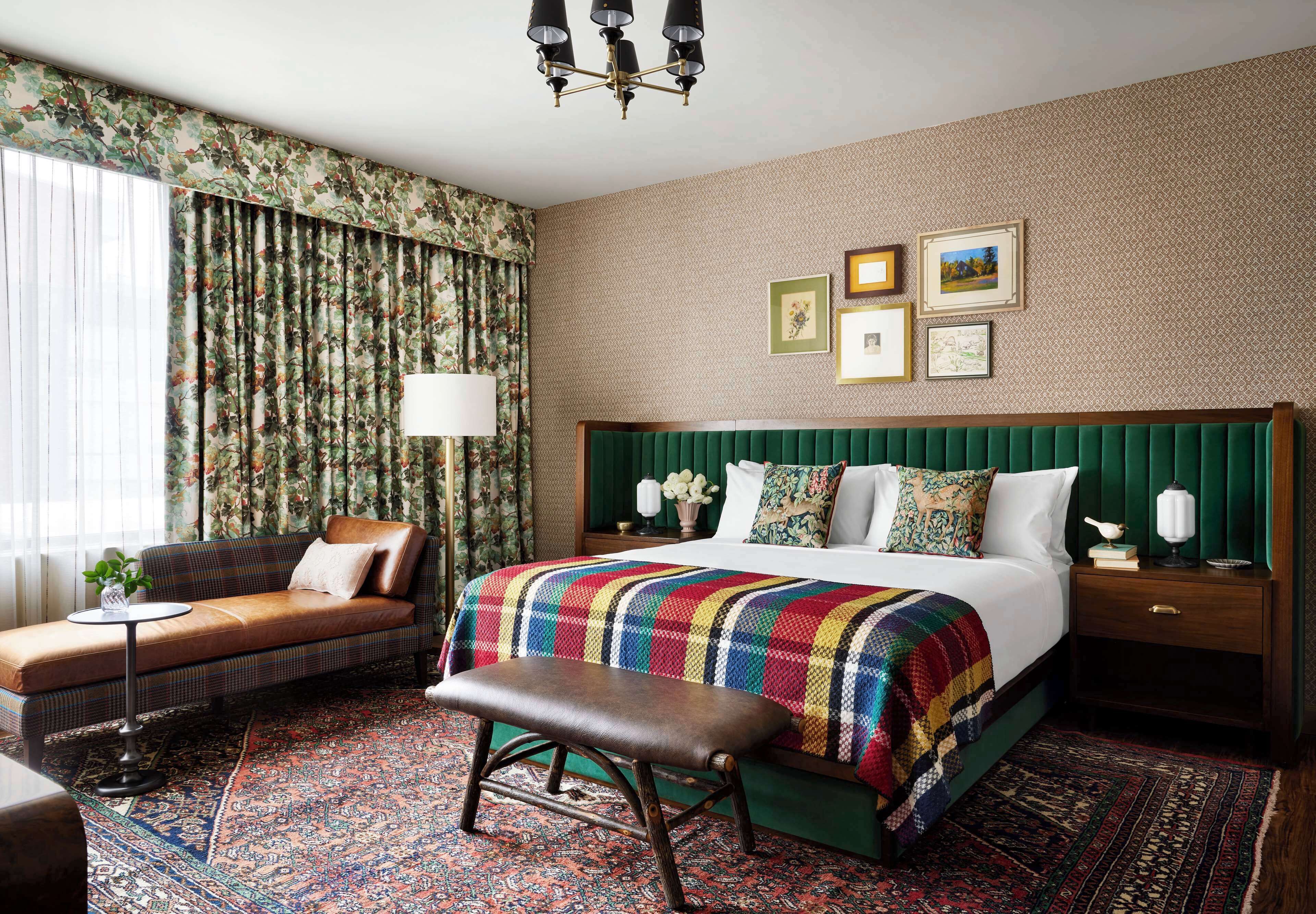 Una habitación de hotel con una cama grande, un banco, un sofá y una mesita de noche.