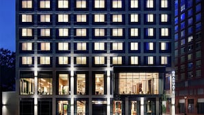 Un hotel de varios pisos con un llamativo letrero que dice “Graduate”, ventanas amplias y una fachada bien iluminada.
