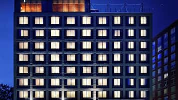 A multi-story hotel with a prominent "Graduate" sign, large windows, and a well-lit facade.