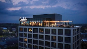 Un hotel con bar en la azotea llamado "Graduate", con mesas al aire libre e iluminación con guirnaldas.