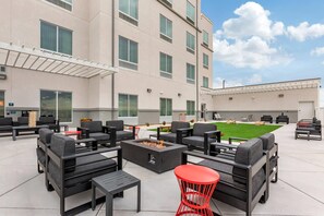 An outdoor seating area with sofas and tables, a fire pit, and a green lawn. - MainStay Suites Carlsbad South (Carlsbad)