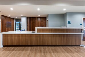 A reception desk with a wooden finish, a refrigerator stocked with beverages, and a blue wall with signage.