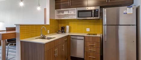A compact kitchen with a dishwasher, a microwave, and a refrigerator.