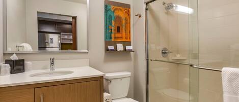 A modern bathroom with a glass shower enclosure, a white sink, and a toilet.