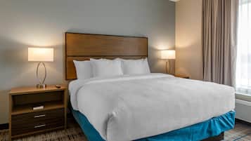A hotel room with a large bed, two bedside tables, a nightstand, a lamp, and a window with curtains.
