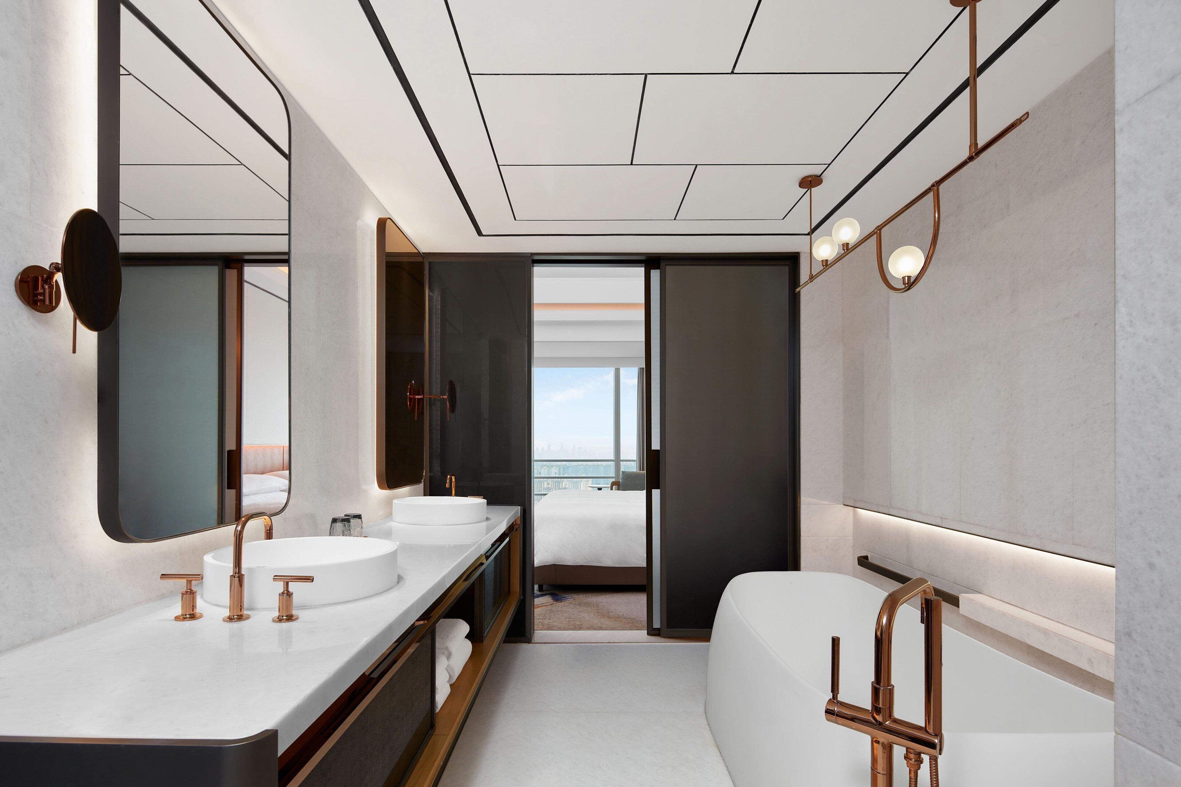 Un baño moderno con un espejo grande, dos lavamanos y una bañera.