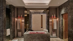 A modern bathroom with a large marble bathtub, a glass-enclosed shower, and marble walls. - Sheraton Guangzhou Panyu (Guangzhou)