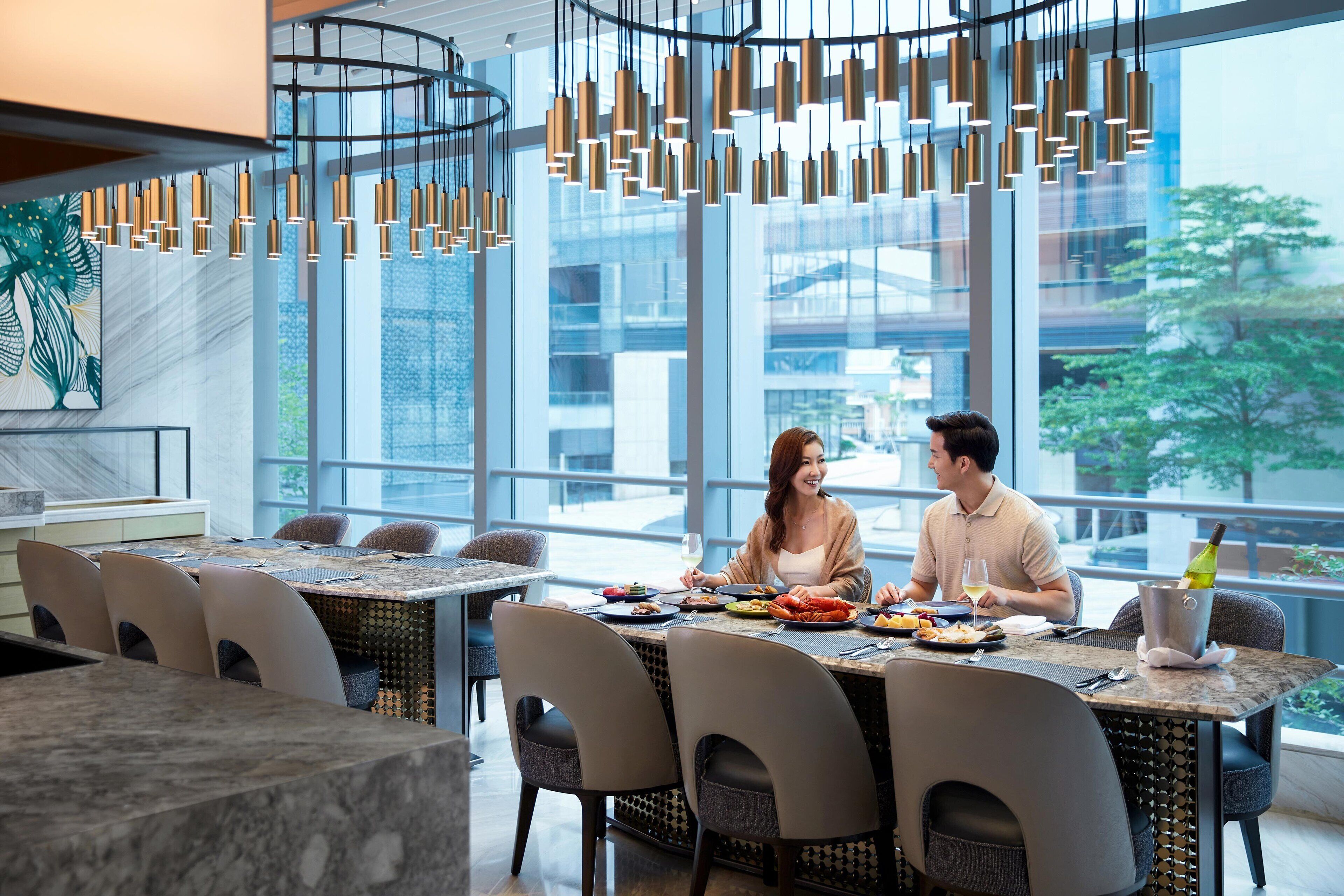 A modern dining area with a large table, chairs, and hanging pendant lights.