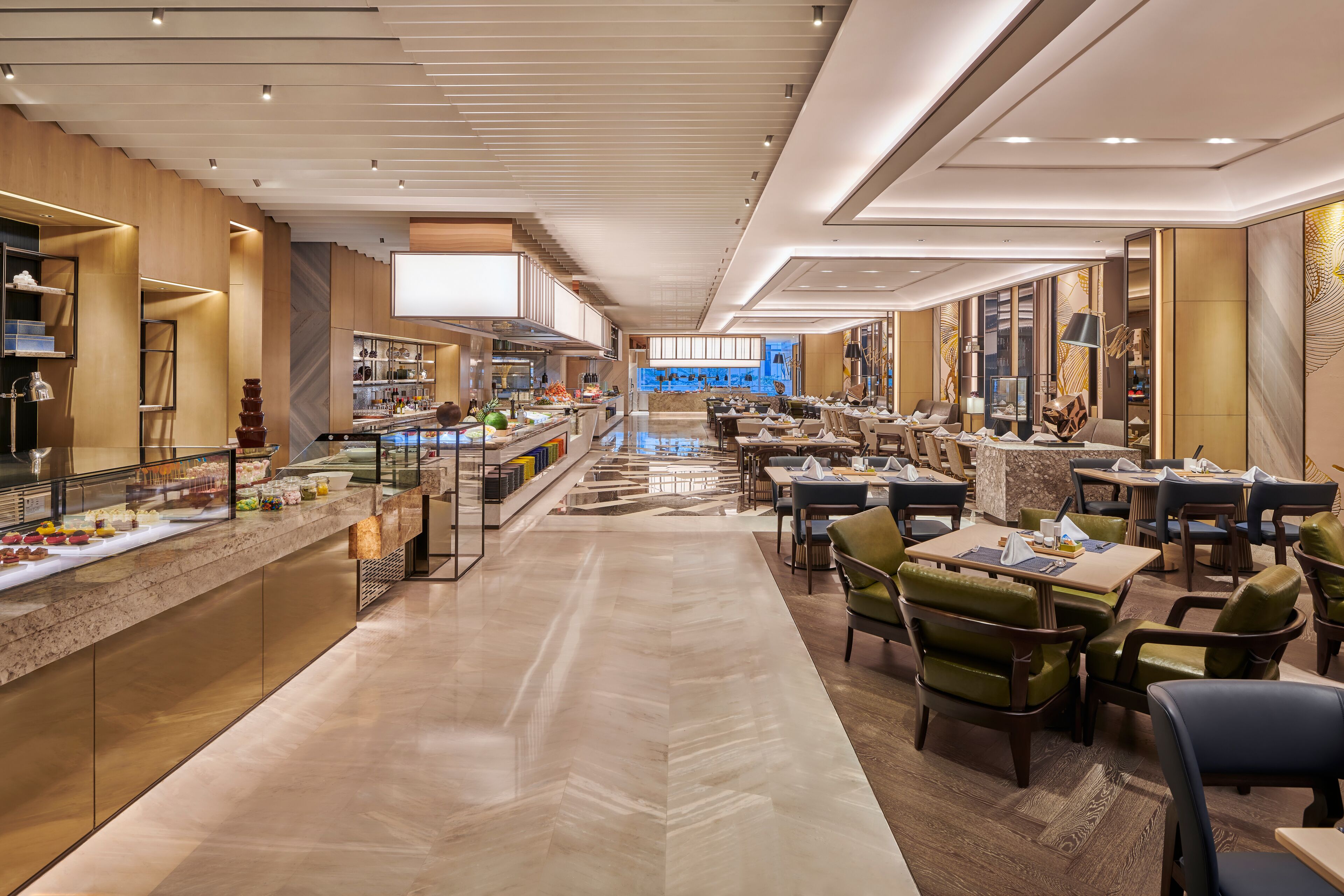 A modern hotel lobby with a central bar area, dining tables, and comfortable seating.