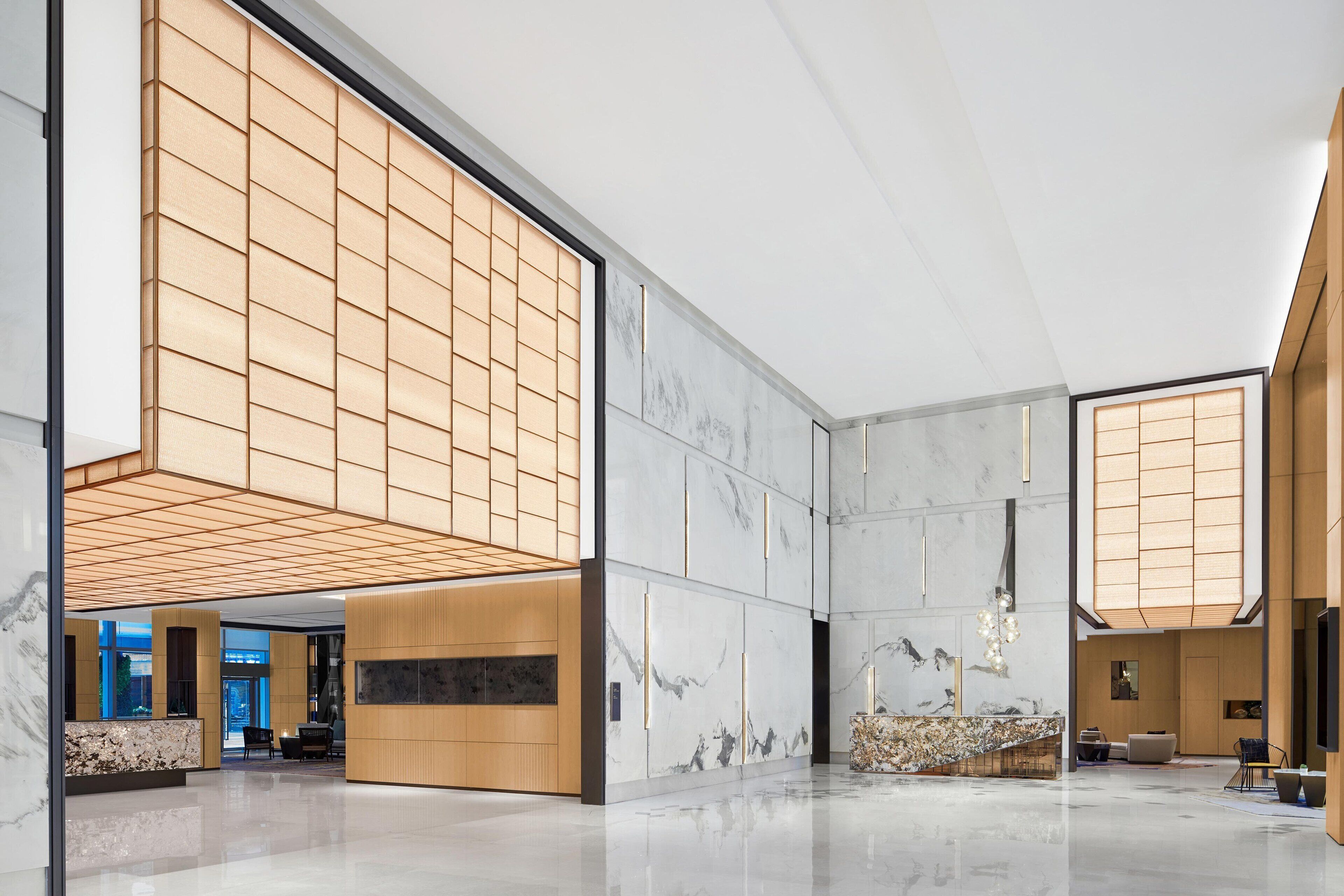 A spacious lobby with a high ceiling, marble walls, and a wooden reception desk.
