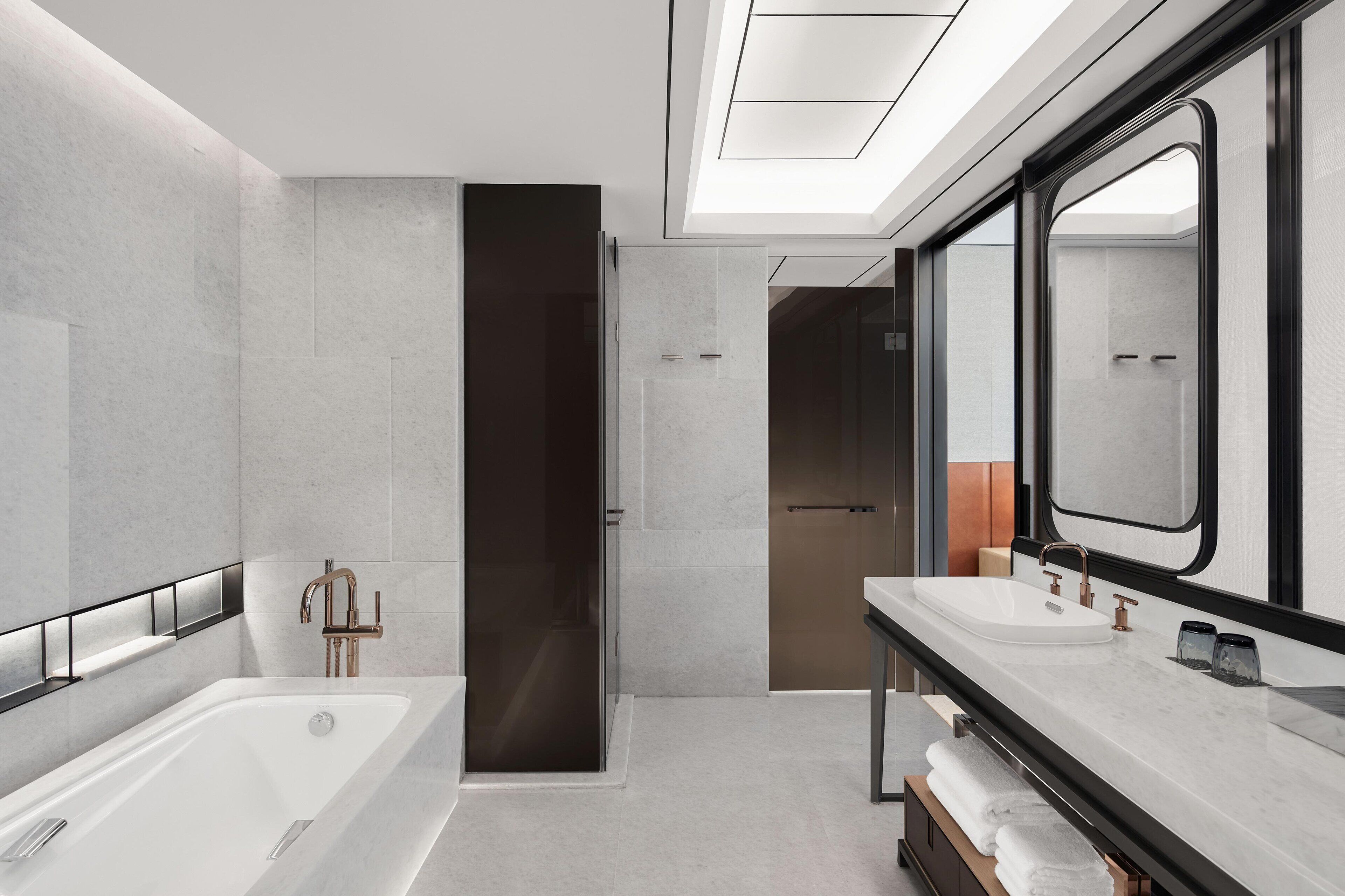 A modern bathroom with a large bathtub, a separate shower area, and a vanity with a mirror.