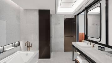 A modern bathroom with a large bathtub, a separate shower area, and a vanity with a mirror.