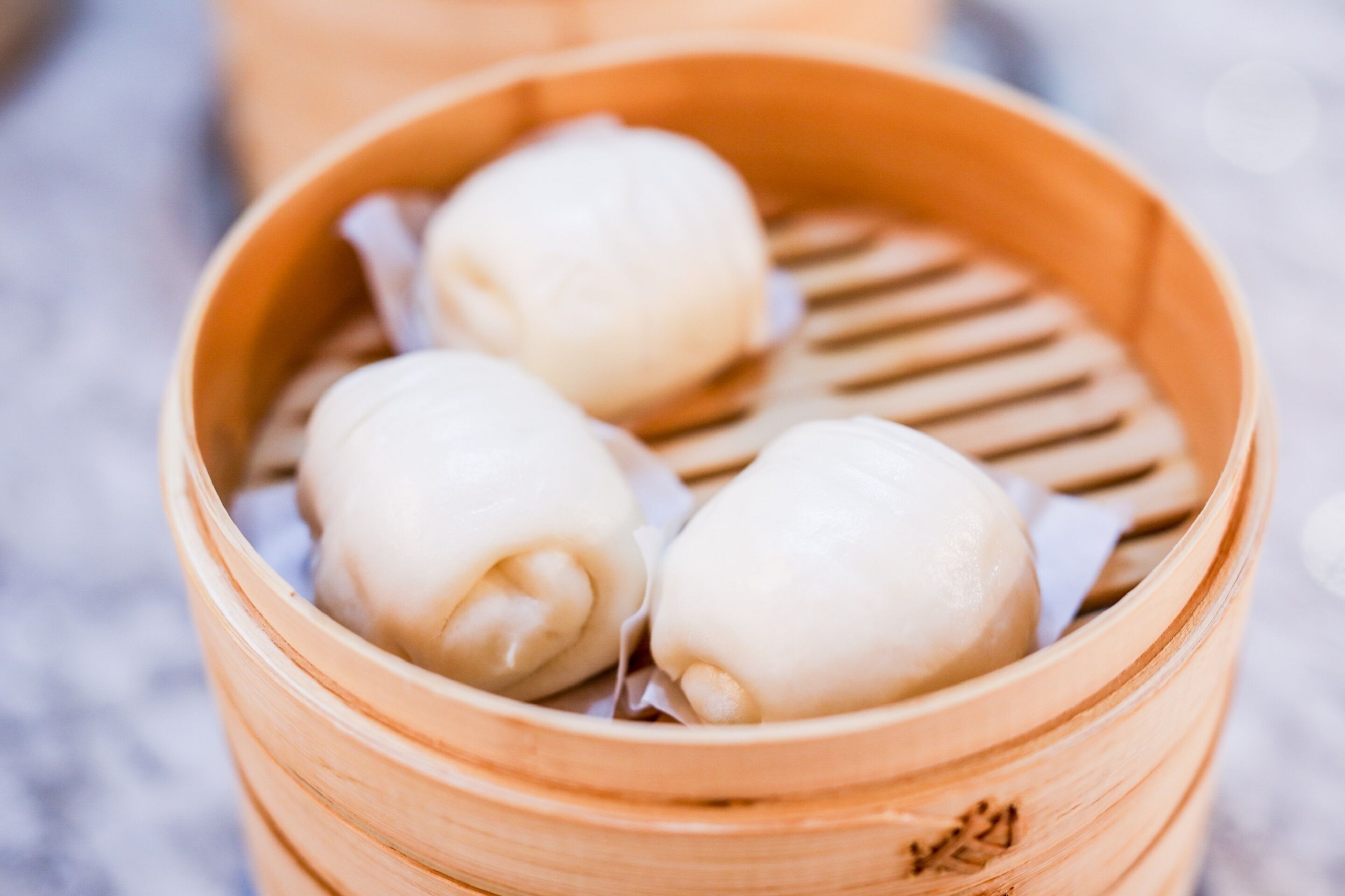 A bamboo steamer with three white dumplings.
