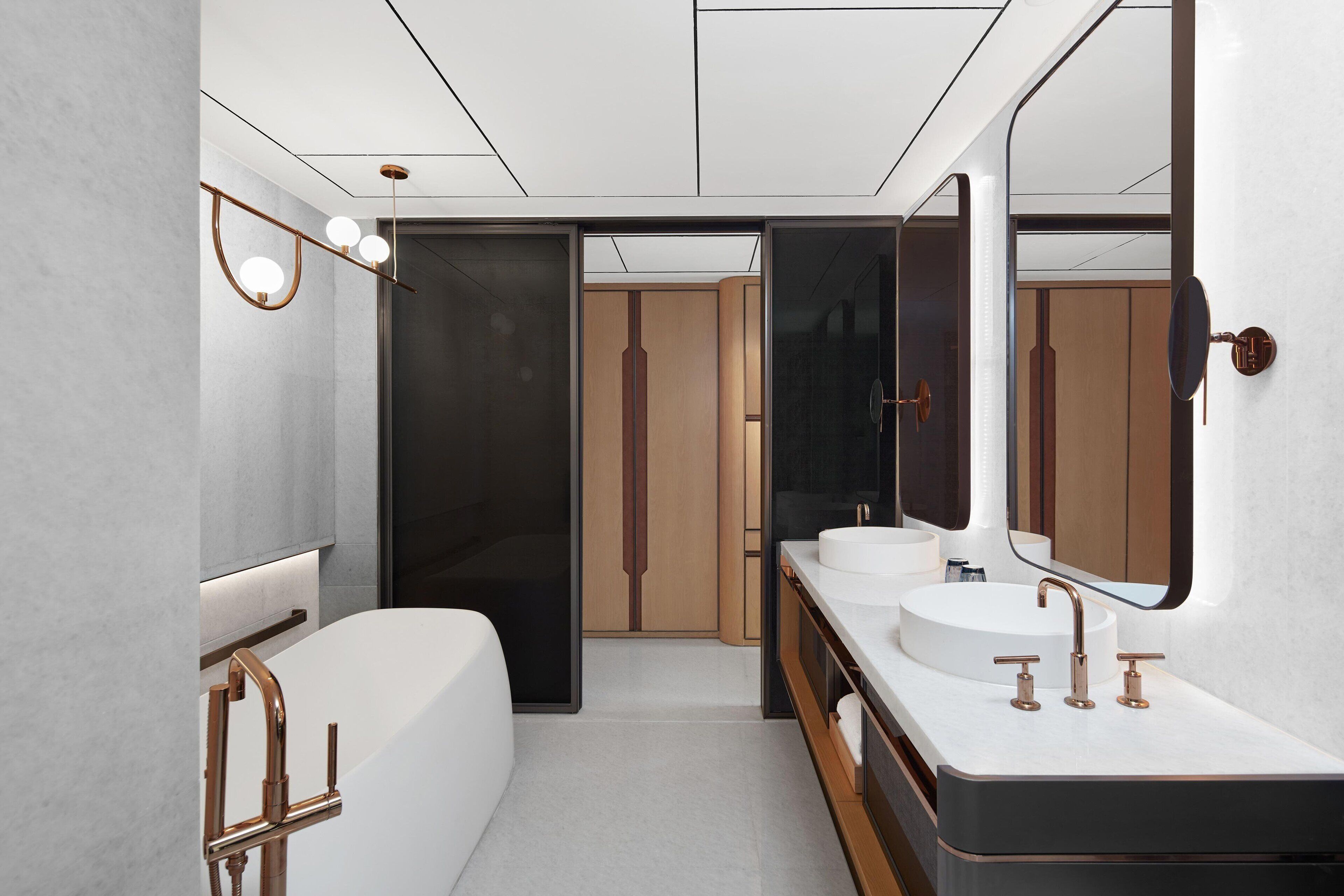 A modern bathroom with a large bathtub, two sinks, and a mirror.