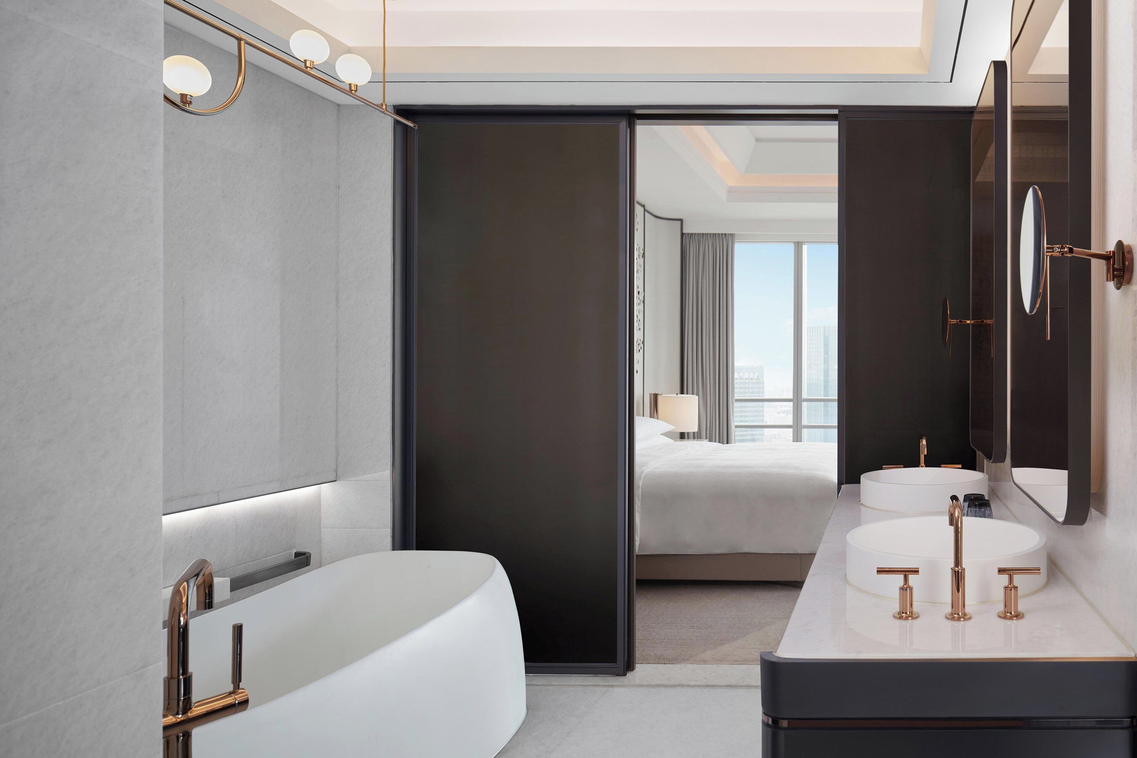 Un baño moderno con una bañera grande, dos lavamanos y un espejo.