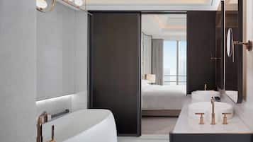A modern bathroom with a large bathtub, two sinks, and a mirror.