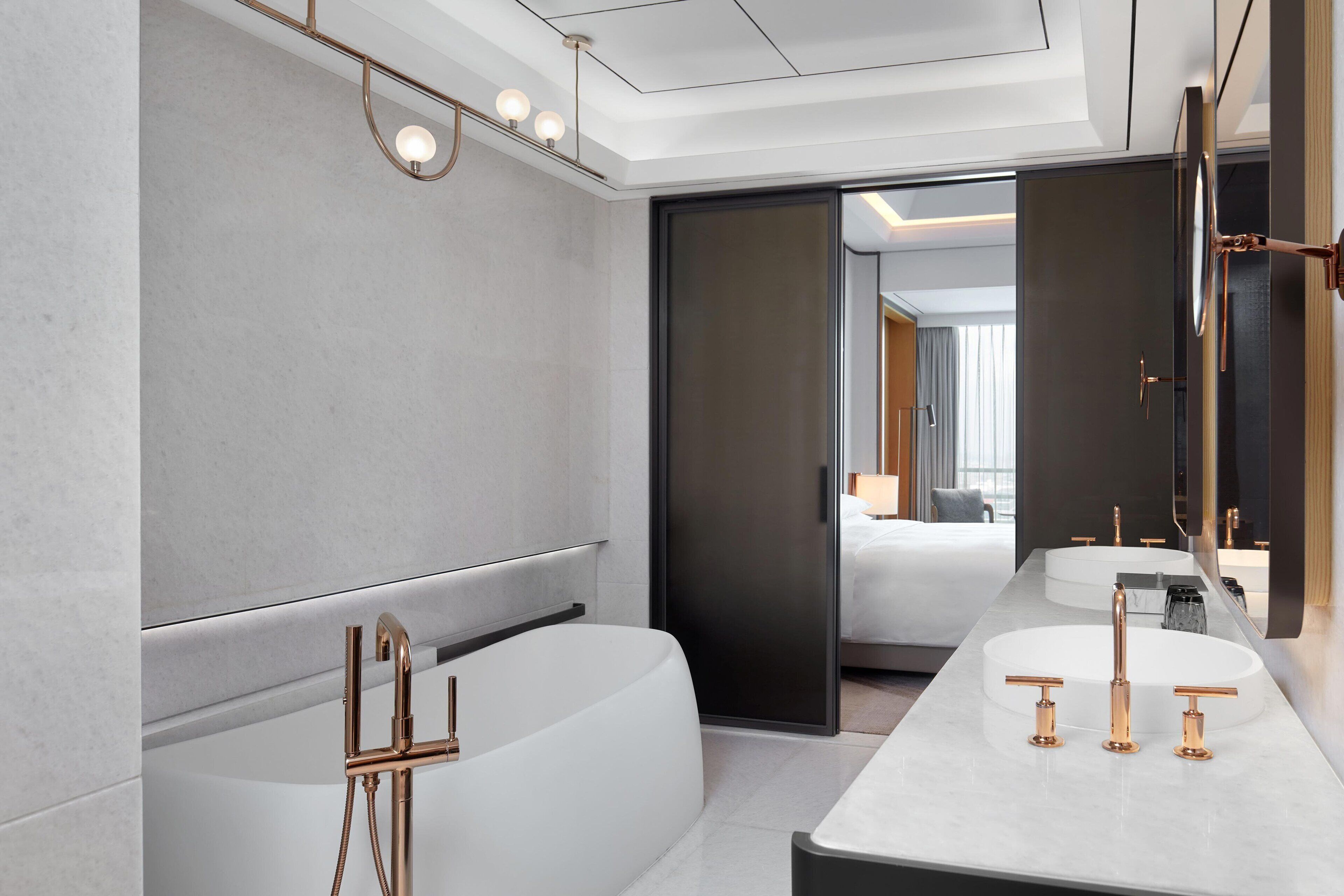 Ein modernes Badezimmer mit einer freistehenden Badewanne, einem Waschtisch mit großem Spiegel und einem separaten Waschbecken.