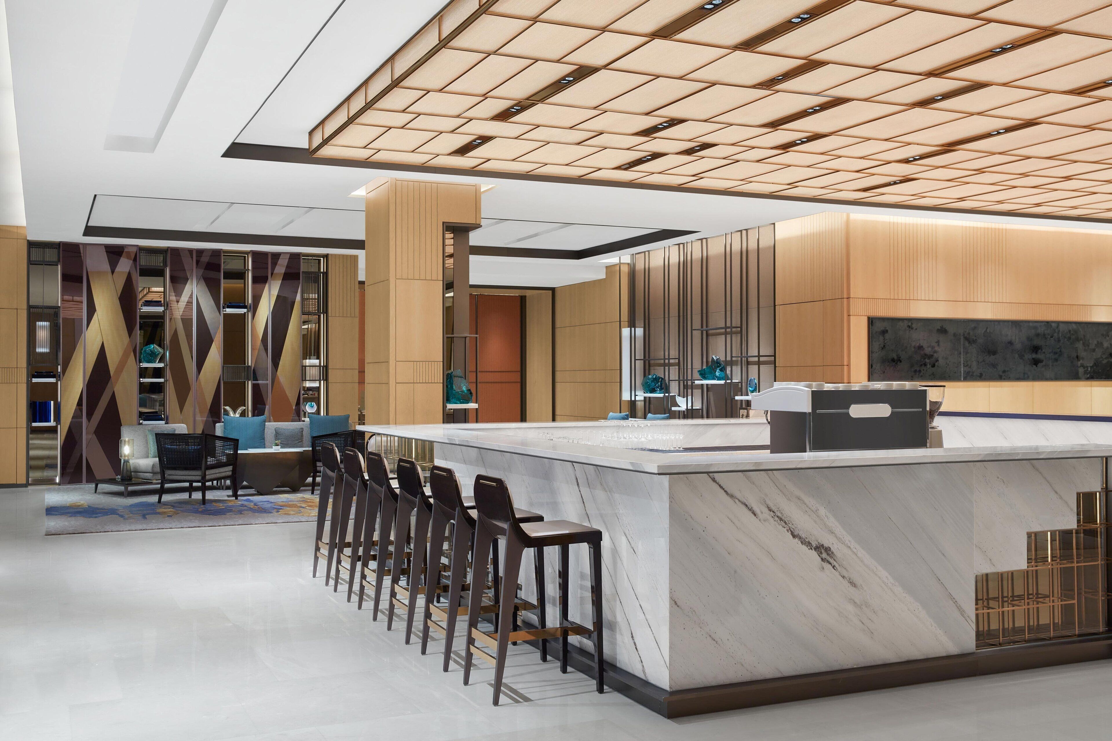 A modern bar area with a marble countertop and bar stools.