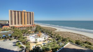 A high-rise hotel with a beach view, a parking lot, and a playground area.