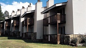 A row of white buildings with balconies and stone foundations.