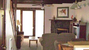 A living room with a fireplace, a ceiling fan, and a framed picture on the wall.